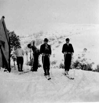 Four skiers preparing to ski at Bogong. Building on left