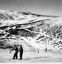 Mountain with an average cover of snow. Skiers walking in the foreground