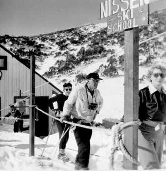 Skiers lined up at the tow beneath a sign for the Nissen Ski School