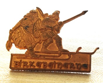Small gold lapel pin featuring Nordic Skiers