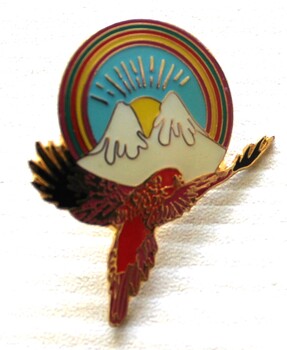 An enamelled badge featuring 2 mountains between the wings of a red bird.