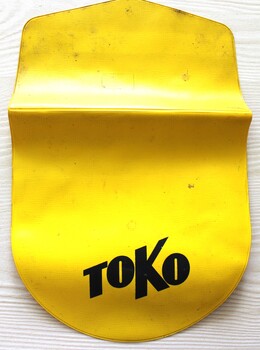 A bright yellow pouch with "Toko" written in black on front
