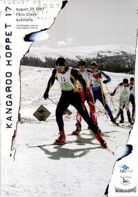 A group of skiers skiing up a gentle slope near a kangaroo traffic sign stuck in the snow.