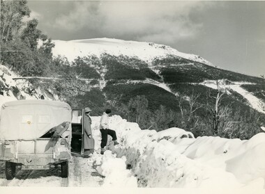 Two people standing beside a truck looking over mountain view.