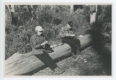 Rel Gibbs and Ray Meyer sitting on log in camp at Gap Saddle.