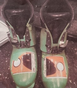 Lime green ski boots with sticker.