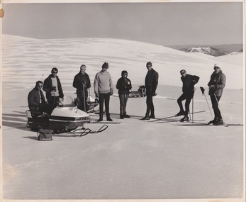 A group of skiers with a snowmobile