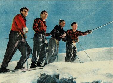 Four men on skies at the top of a slope