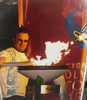 Steve Lee lights the cauldron at the Hotham Village after carrying it down the mountain,