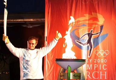 Steve Lee lights the cauldron at the Hotham Village after carrying it down the mountain,