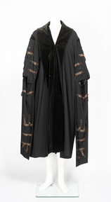 Black ceremonial mayoral robe with velvet collar and black tassel and leather detail on sleeves.