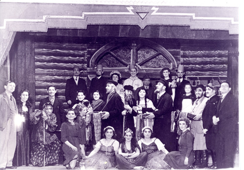 Black and white photo of a large group on stage in costumes 