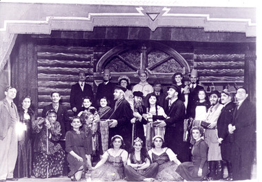 Black and white photo of a large group on stage in costumes 