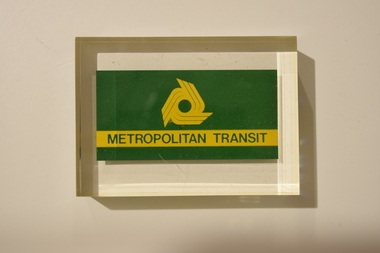 A transparent paperweight with an opaque printed logo (visible from both sides) of the Metropolitan Transit Authority within the item.