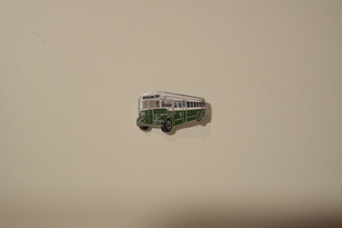 A metallic badge in the likeness of an AEC Regal Mk3 bus, presumably for commemorative purposes.