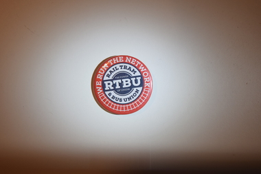 A metal round badge advertising the Rail Tram & Bus Union (RTBU).