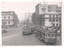 A bustling city street scene with trams and cars. A large advertisement for "HAVELOCK" tobacco is visible on the side of a building.