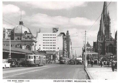 Photograph of Swanston Street, Melbourne, showing trams on the street, a domed building, Flinders St station on the left and a gothic-style church spire of St Paul's cathedral on the right.