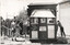 A group of young men stand around a wooden signal box with signs indicating "SIGNAL LIGHTS FOR TRAMS ONLY" and "UNAUTHORISED PERSONS ARE NOT PERMITTED IN THIS SIGNAL BOX."