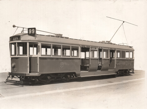 A vintage tram numbered 670 and labeled "CITY" is shown from the side. The tram has multiple windows and doors and is equipped with a trolley pole.