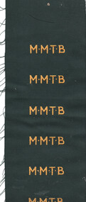 MMTB Uniform Name badge on green cloth sewn in yellow letters.