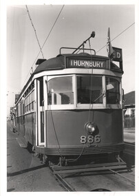 Low-angle shot of a vintage tram numbered 886. The tram has a sign above the windshield that reads "THORNBURY" and a destination sign indicating "9D". The tram is on tracks with overhead power lines.