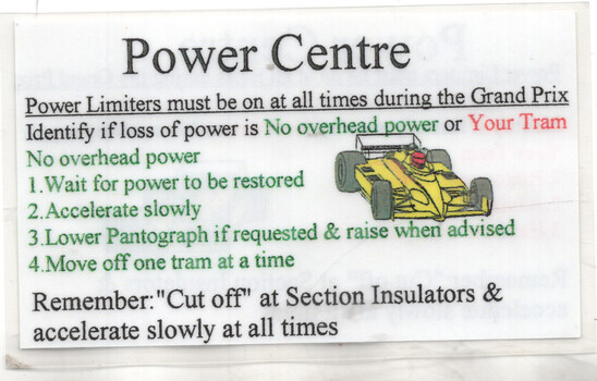 Sign titled "Power Centre" with instructions for power limiters during a Grand Prix, including identifying power loss, waiting for restoration, accelerating slowly, and managing pantographs, alongside a cartoon yellow race car.