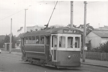 A vintage green and cream tram, number 177, with "BALLARAT RD" sign above the driver's cabin, travels on an urban street.