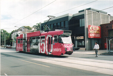 A bright pink tram on a street, advertising "150 years" of "the royal women's hospital," with large black text and images of women on its side.