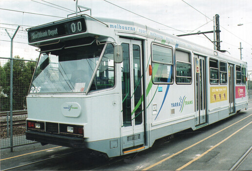 A white Yarra Trams tram with green and blue accents is parked on tram tracks. The tram has a destination board reading "Southbank Depot 00" and the number "236" is visible on the front. Advertisements are visible on the side of the tram.