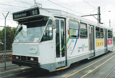 A white Yarra Trams tram with green and blue accents is parked on tram tracks. The tram has a destination board reading "Southbank Depot 00" and the number "236" is visible on the front. Advertisements are visible on the side of the tram.
