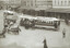 A busy city street scene with horse-drawn carts and cable trams, showing passengers riding on open-sided tram cars labeled "Carlton South Yarra & Prahran."  One of the cable trams is being towed by a truck.