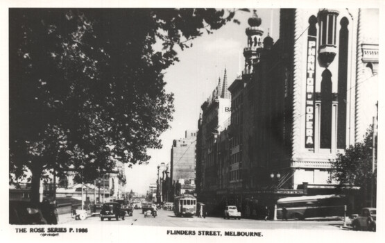Black and white vintage photograph of a bustling city street with vintage cars and a tram. A large tree partially shades the left side of the image, with its branches extending over the street. The right side features ornate architecture, including a building with "PHANTOM OF THE OPERA" prominently displayed vertically. The street is lined with multi-story buildings and shows activity with vehicles and a tram in motion. The bottom text reads "FLINDERS STREET, MELBOURNE."
