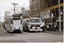A white tram recovery vehicle with "TRAM RECOVERY VEHICLE" written on its side is positioned alongside a stopped tram on a city street.