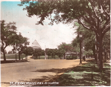 Vintage image of St. Kilda Road, Melbourne, with a green tram approaching a large domed building in the distance.