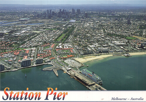 Aerial view of Station Pier in Melbourne, Australia, with a ship docked, a sandy beach, and the city skyline in the background.
