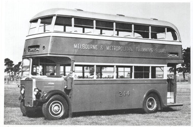 Vintage double-decker bus with "Melbourne & Metropolitan Tramways Board" text and the number 244 on its side, parked on a grassy field.