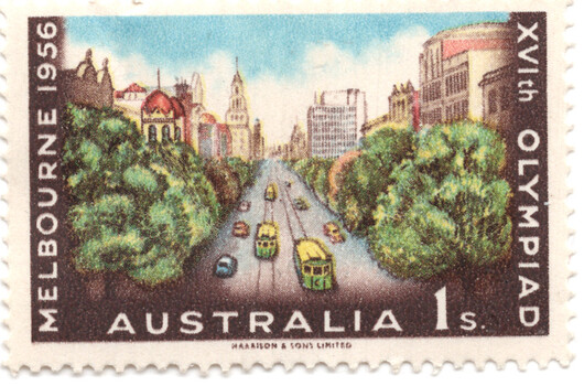 Stamp commemorating the 1956 Melbourne Olympics, featuring a scenic view down a wide avenue lined with trees and ornate buildings, with trams and cars on the road.