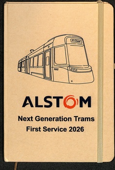 A notebook with an illustration of a modern tram on the cover, below which is the Alstom logo and the text "Next Generation Trams First Service 2026".