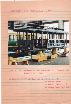 Heritage car undergoing restoration in a workshop, with handwritten notes detailing its history and restoration date.