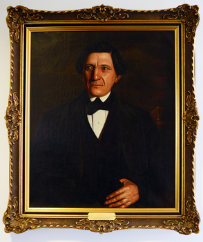 A painted portrait of a man in mid-nineteenth century black formal clothes.