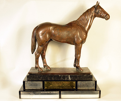 A bronze horse statuette on a marble and wood base.