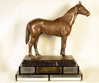 A bronze horse statuette on a marble and wood base.