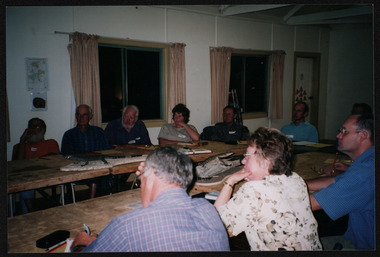 Colour photograph of ten people seated around a u-shaped table setting all looking towards a speaker (not visible).