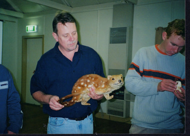 Colour photograph of 'Queries about quolls' presenter Andrew Murray holding a mounted quoll specimen, alongside an event attendee. 
