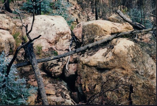 A pile of large boulders with a couple of tree logs lying on top