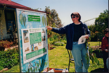 Photograph showing two women looking at a large sign outside Tatong Tavern. 