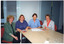 COL photo of four people sitting around the end of a table, with some printed publications on the table in front of them.