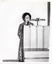 B&W photo of a woman standing at a large wooden podium, speaking.