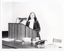 B&W photo of a woman standing at a podium, speaking. The podium is built into a large wooden desk.